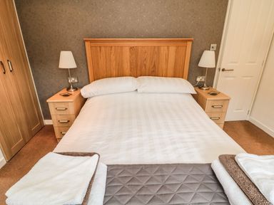 A bedroom with a bed between two bedside tables and lamps at Hillside View in Alnwick