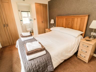 A bedroom with a double bed towels on the foot of the bed bedside tables lamps and an adjoining bathroom at Hillside View in Alnwick