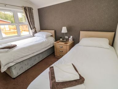 A bedroom with two single beds and a nightstand with a lamp between them at Hillside View in Alnwick