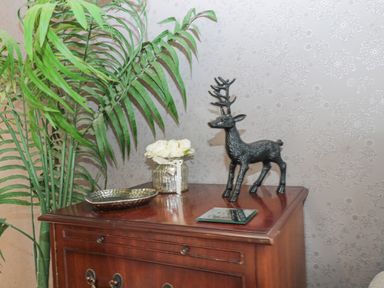A wooden cabinet with a decorative deer statue a small bouquet of flowers a metal dish and a green plant next to it at Hillside View in Alnwick