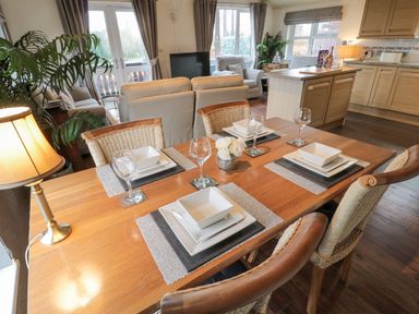 A dining table set with plates bowls and wine glasses in a combined kitchen and living room at Hillside View in Alnwick