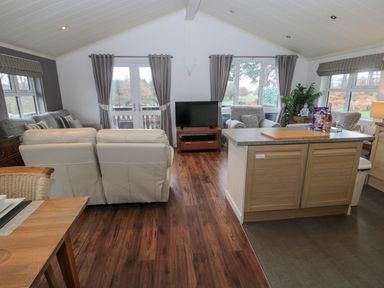 A living room with sofas a TV and a kitchen island at Hillside View in Alnwick