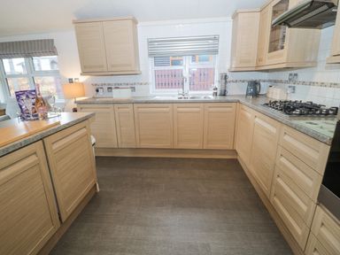 A kitchen with wooden cabinets gas stove kettle and sink at Hillside View in Alnwick