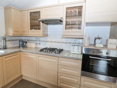 A kitchen with wooden cabinets gas stove electric oven toaster and kettle at Hillside View in Alnwick