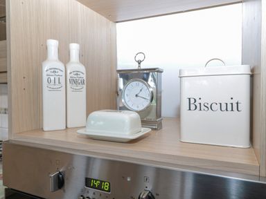 A kitchen shelf with oil and vinegar bottles a butter dish a clock and a biscuit tin at Hillside View in Alnwick