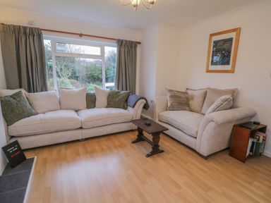 A living room with beige sofas and green curtains and a small wooden table at Sea Change in Newholm near Whitby