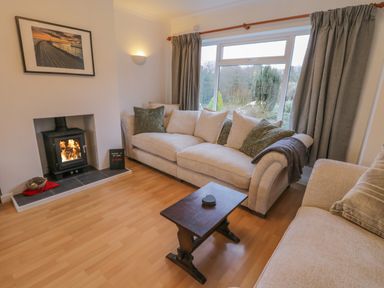 A living room with a wood burning stove two beige sofas and a wooden coffee table at Sea Change in Newholm near Whitby