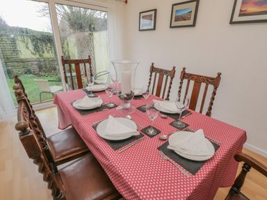 A dining room with a table set for six with plates glasses and a candle holder at Sea Change in Newholm near Whitby