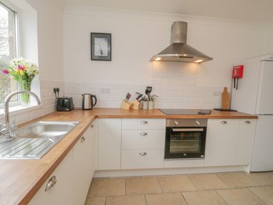 A kitchen with wooden countertops a stainless steel sink a kettle toaster and oven at Sea Change in Newholm near Whitby