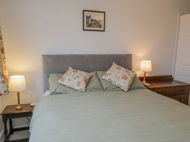 A bedroom with a bed with floral pillows and two bedside tables with lamps at Sea Change in Newholm near Whitby
