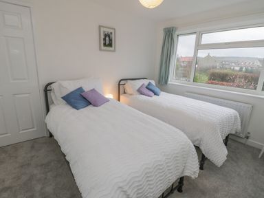 A bedroom with two single beds and a large window at Sea Change in Newholm near Whitby