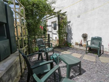 A patio area with plastic chairs and a small table surrounded by plants at Sea Change in Newholm near Whitby