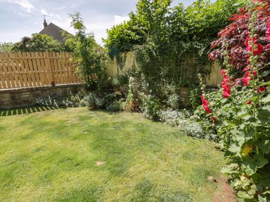 A garden with grass lawn flowers and shrubs next to a wooden fence at Sea Change in Newholm near Whitby