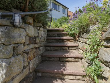 Stone steps with stone walls on either side and plants growing along the walls leading up to a house at Sea Change in Newholm near Whitby