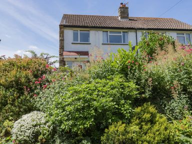 A garden with bushes and flowers in front of a semi detached house at Sea Change in Newholm near Whitby