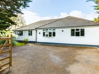 A single-story house with white walls and a tiled roof with a wooden gate and a gravel driveway at The Garden House in Rock