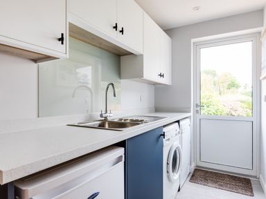 A laundry room with a sink washing machine dryer and a door leading outside at The Garden House in Rock