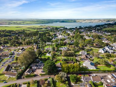 An aerial view of a residential neighborhood with houses trees and a body of water in the distance at The Garden House in Rock