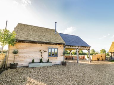 A wooden house with a gravel driveway and potted plants at The Hyde in Armscote near Newbold on Stour