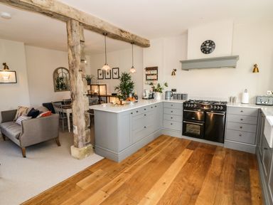 A kitchen and dining area with wooden flooring a grey couch wooden dining table and light fixtures at The Hyde in Armscote near Newbold on Stour