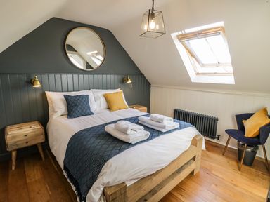 A bedroom with a wooden bed with folded towels on it and skylight window at The Hyde in Armscote near Newbold on Stour