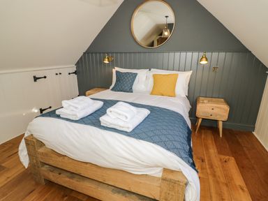 A bedroom with a wooden bed blue and yellow pillows and bedside tables at The Hyde in Armscote near Newbold on Stour