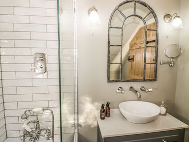 A bathroom with a white sink on a gray cabinet a decorative mirror and a wooden door at The Hyde in Armscote near Newbold on Stour