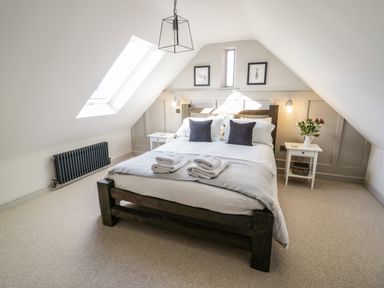 A bedroom with a wooden bed and two nightstands under a slanted ceiling at The Hyde in Armscote near Newbold on Stour