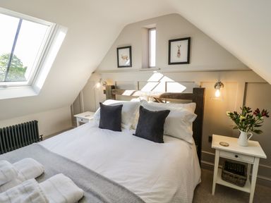 A bedroom with a double bed under a sloped ceiling with a skylight and bedside tables at The Hyde in Armscote near Newbold on Stour