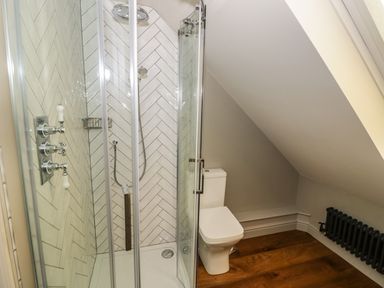 A bathroom with a glass shower enclosure and a toilet under a sloped ceiling at The Hyde in Armscote near Newbold on Stour