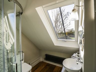 A bathroom with a shower cabin toilet sink and slanted skylight window at The Hyde in Armscote near Newbold on Stour