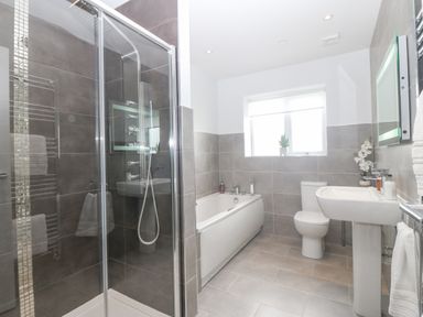 A bathroom with a shower enclosure a bathtub a toilet a sink and a window at Berllan Llanbedrgoch near Benllech