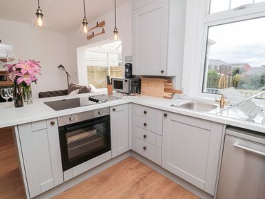 A kitchen with white cabinets a stove oven a microwave a sink and flowers in a vase at Shileen in Seahouses