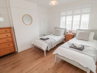 A bedroom with two single beds a wooden chest of drawers and a small bedside cabinet at Shileen in Seahouses