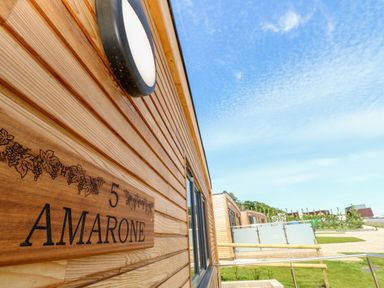 The exterior of a wooden building with a sign reading Amarone number 5 and a circular light above at Amarone in Seaview