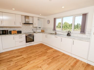 A kitchen with white cabinets wooden floor a window and appliances at Amarone in Seaview