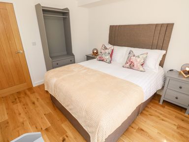 A bedroom with a bed with pillows and a blanket two bedside tables with lamps and an empty wardrobe at Amarone Seaview