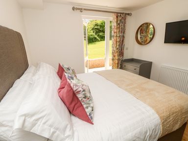 A bedroom with a bed with pillows and a throw blanket and an open door leading to a garden at Amarone Seaview