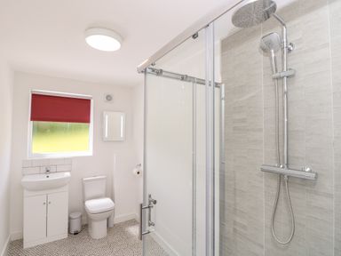 A bathroom with a shower enclosure a toilet a sink cabinet and a window with a red blind at Amarone Seaview