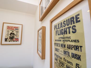Framed vintage posters on a white wall featuring the Isle of Wight Festival 1969 and Pleasure Flights at Ryde's New Airport at Amarone Seaview