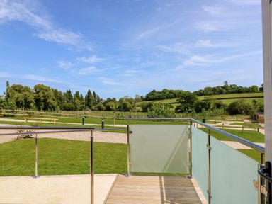 A balcony with metal and frosted glass railing overlooking a grassy area with trees and hills at Amarone in Seaview