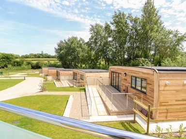 A row of wooden cabins with decks and railings near green lawns and trees at Amarone in Seaview