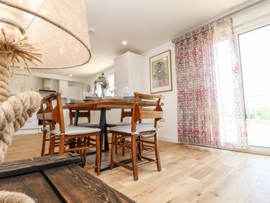A dining area with a wooden table and chairs next to pink patterned curtains and a sliding glass door at Champagne Seaview