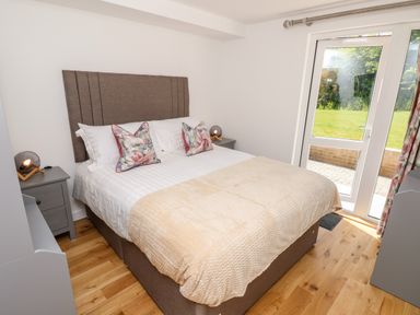 A bedroom with a double bed two side tables and glass door leading outside at Champagne in Seaview
