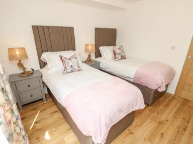 A bedroom with two single beds bedside tables lamps and floral cushions at Champagne in Seaview