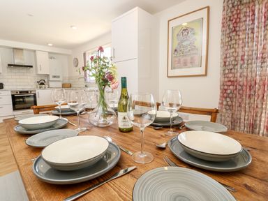 A dining table set with plates bowls wine glasses and a bottle of wine in a kitchen at Barolo in Seaview