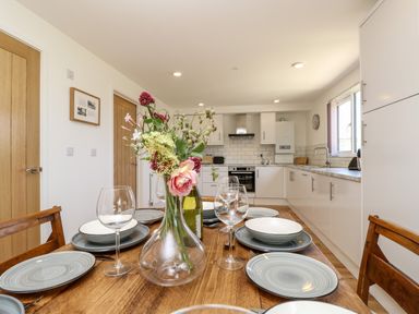 A kitchen with white cabinets a wooden dining table set with plates glasses and flowers at Barolo in Seaview