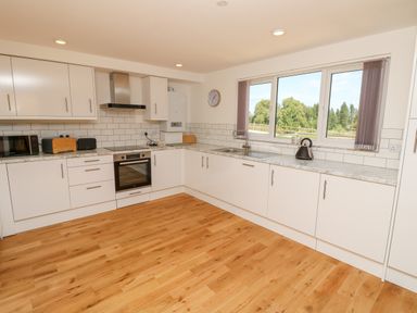A kitchen with white cabinets wooden floor and a window showing trees outside at Barolo in Seaview