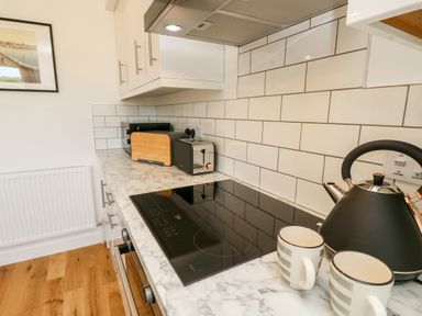 A kitchen countertop with an induction stove, kettle, two mugs, toaster, microwave, and cutting board at Barolo in Seaview