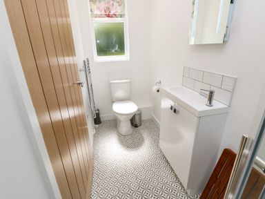 A bathroom with a toilet a sink a mirror a window and patterned floor tiles at Barolo in Seaview